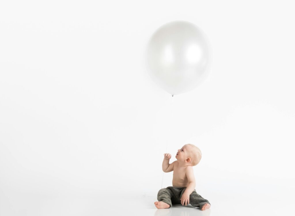 Topless Toddler With Pants Sitting on White Surface While Looking Up