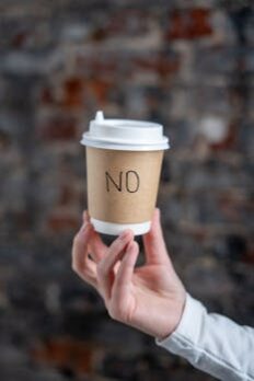 A Person Holding a Paper Cup with the Word No