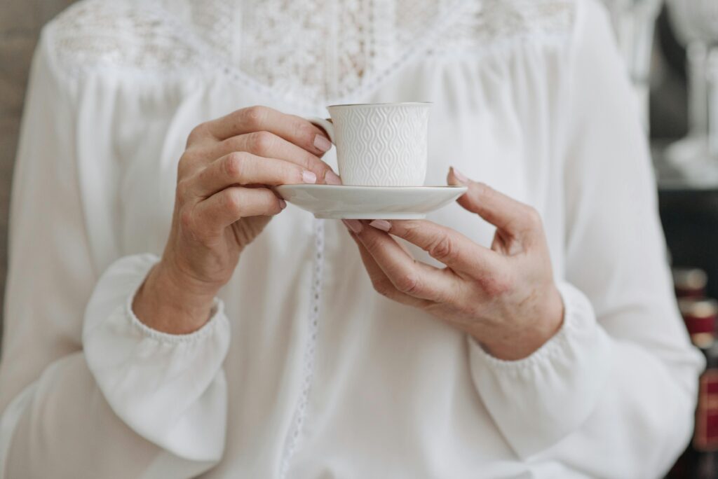 Close-Up Shot of a Person Holding a Cup of Tea on a Saucer